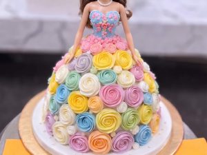 Rainbow Rosette Doll Cake in Lahore — A doll cake whose gown is piped in pastel rainbow rosettes — peach, lemon, mint, blue and lilac swirled togeth