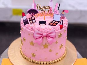 Barbie Glam Birthday Cake in Lahore — A hot pink glam cake with a fondant bow, gold stars across the sides and a full makeup set on top with the bir