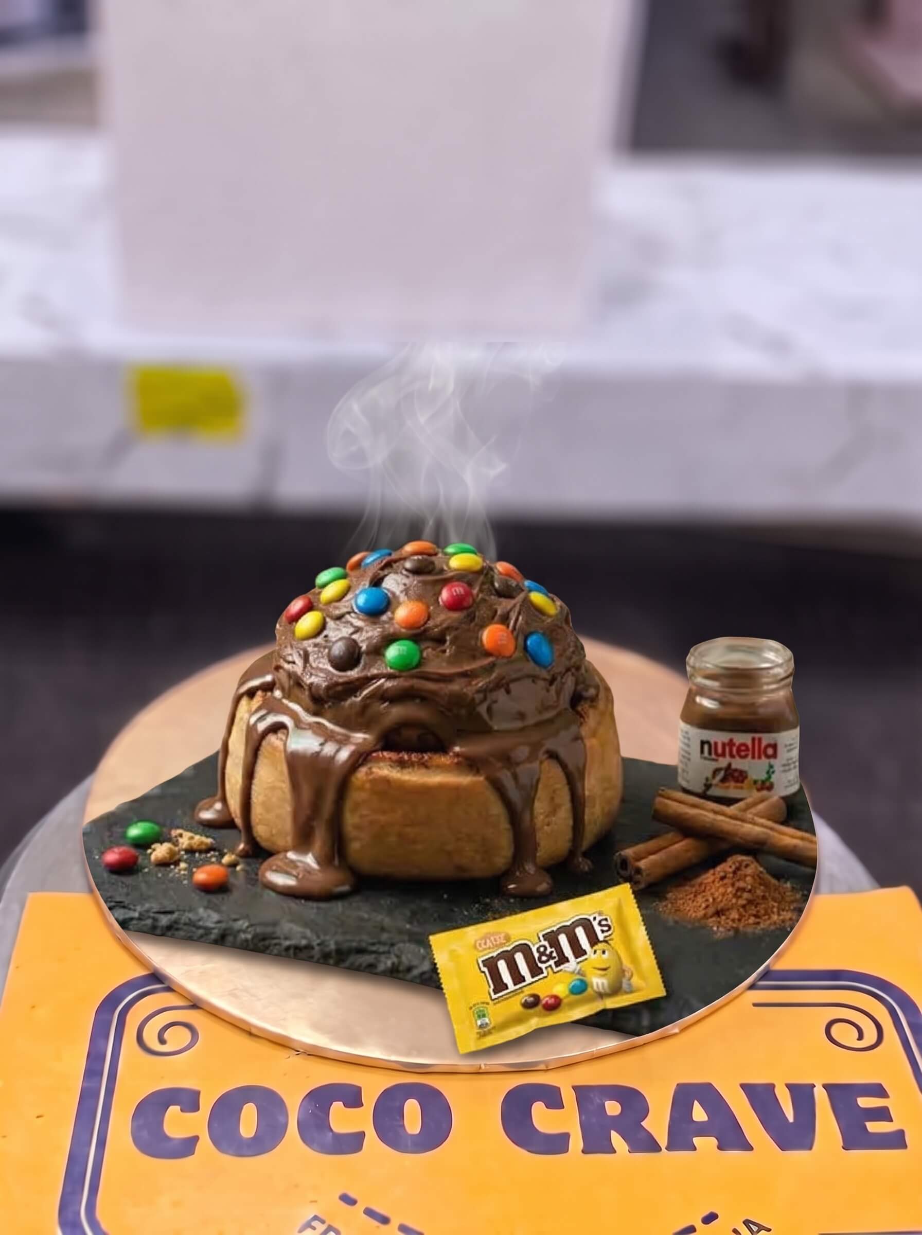 Nutella and M&Ms Loaded Cinnamon Roll in Lahore | CocoCrave.pk Nutella and M&Ms Loaded Cinnamon Roll in Lahore by CocoCrave.pk