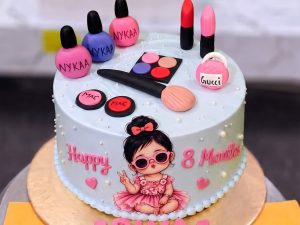 Doll Makeup Kit Cake for Girls in Lahore — A pale blue and white cake spread with fondant makeup — palette, lipsticks, nail polish and blush — around a p