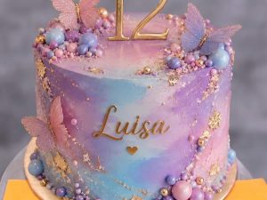 Barbie Butterfly Galaxy Cake in Lahore — A pastel watercolour cake washed in pink, lilac and blue, with 3D butterflies climbing the side, a gold name a