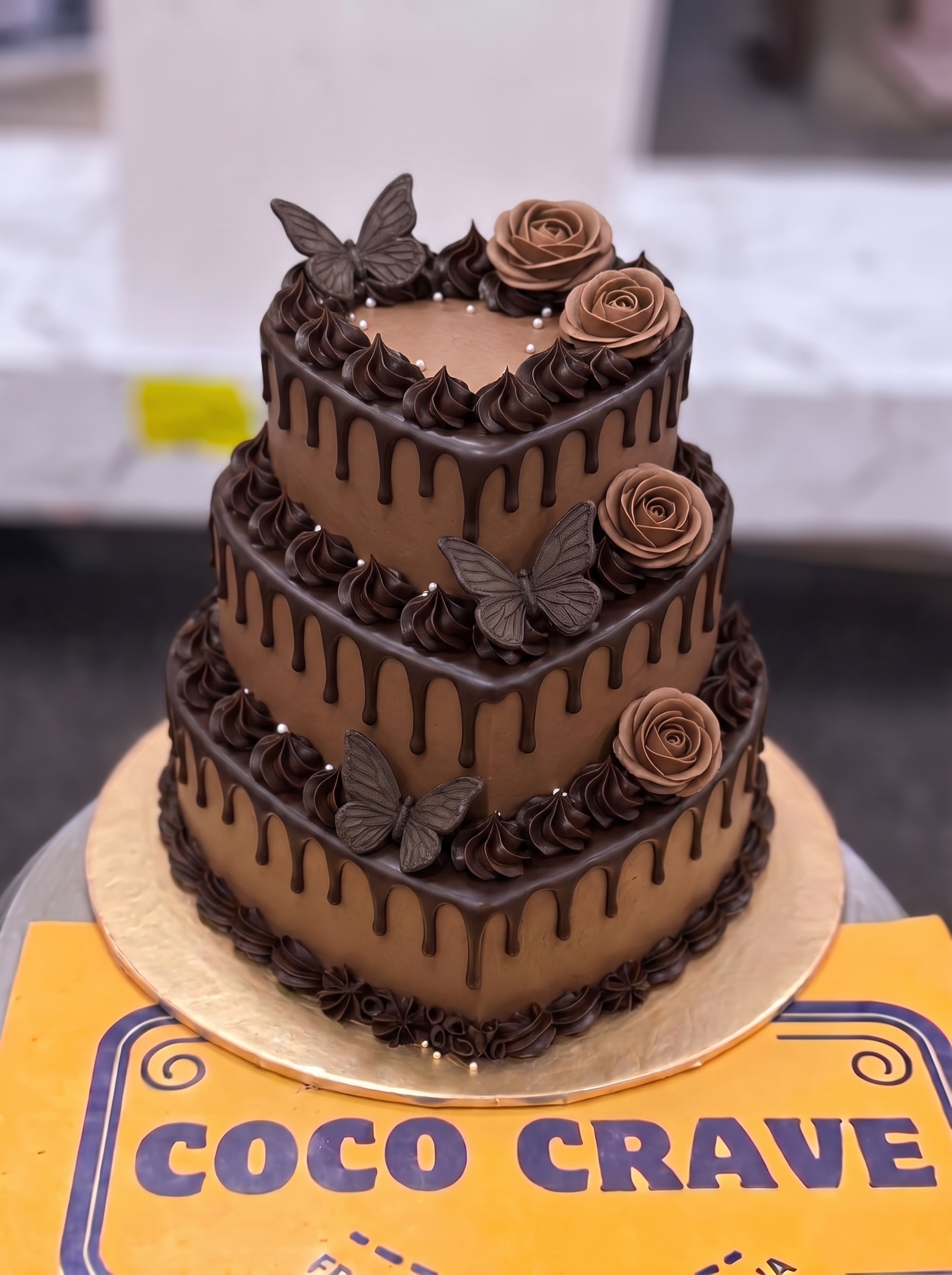 Three Tier Chocolate Rose Cake in Lahore — Coco Crave Lahore Three Tier Chocolate Rose Cake in Lahore — A three tier chocolate cake with piped chocolate roses, butterflies and a drip on every tier — an elegant larg