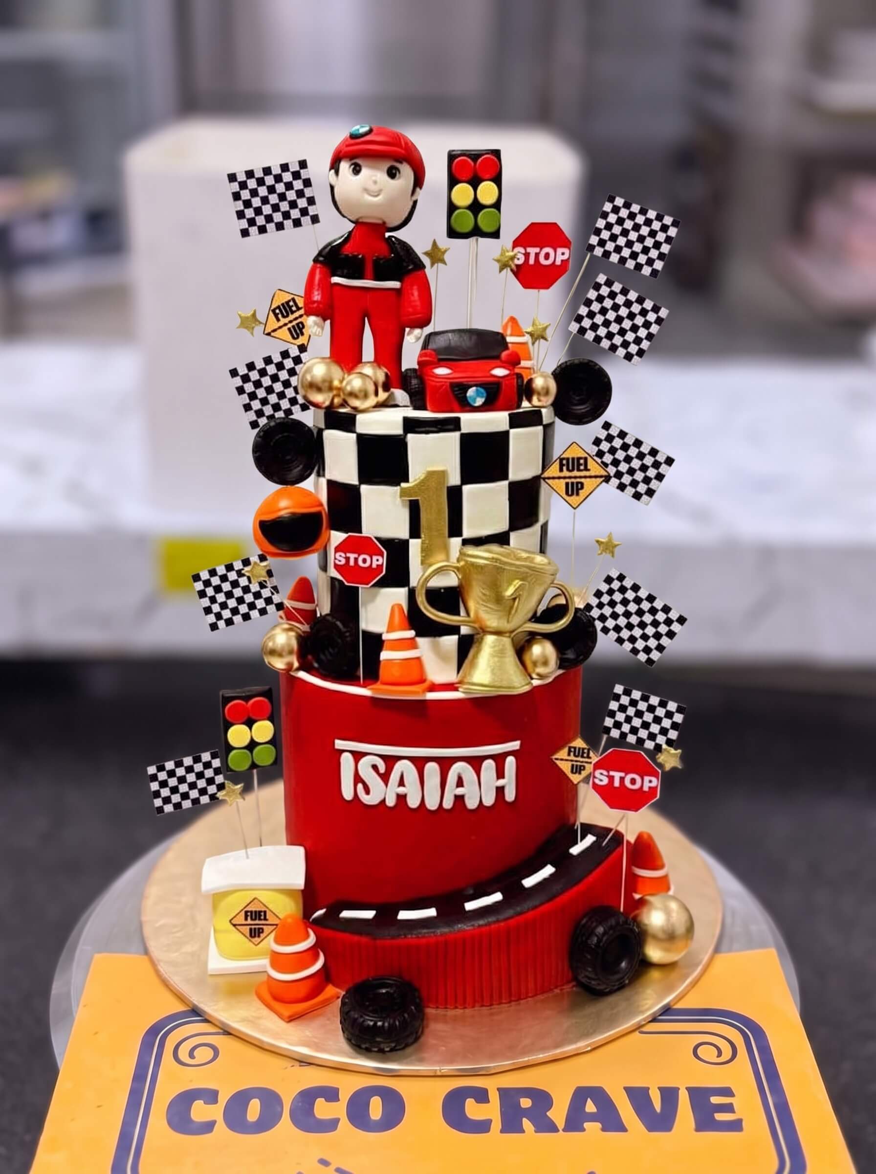 Race Champion Trophy Cake in Lahore — CocoCrave.pk Race Champion Trophy Cake in Lahore by CocoCrave.pk — three tier racing champion cake in red, black and gold