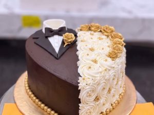 Tuxedo and Gown Chocolate Wedding Cake in Lahore — A tuxedo-and-gown heart cake in dark chocolate and ivory rosettes, edged with gold pearls — a chocolate weddin