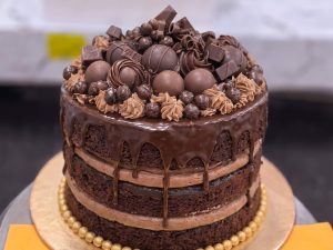 Chocolate Truffle Cake in Lahore — A semi-naked chocolate truffle cake crowned with hand-rolled truffle balls, chocolate pearls and a caramel dri