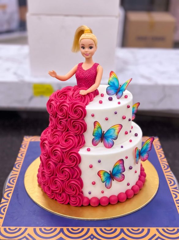 Two Tier Barbie Butterfly Cake in Lahore — A two tier Barbie cake — a magenta rosette tier below, a white tier scattered with printed butterflies above,