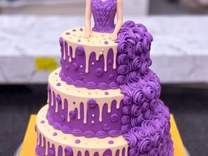 Purple Drip Doll Cake in Lahore — A three tier doll cake in purple rosettes with a white chocolate drip running over every tier and the doll sta