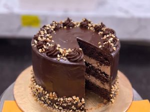 Chocolate Nut Fudge Cake in Lahore — A glossy chocolate fudge cake coated in crushed nuts around the base with a smooth ganache top — a rich chocol
