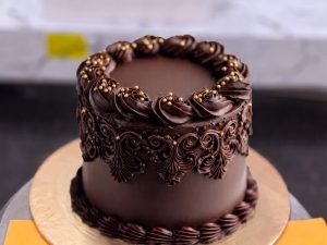 Chocolate Ganache Celebration Cake in Lahore — A smooth dark chocolate ganache cake finished with hand-piped scrollwork around the sides — our most classic c