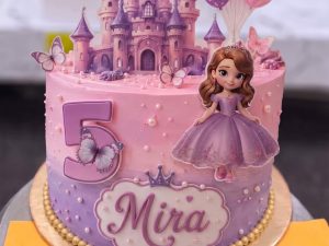 Princess Castle Birthday Cake in Lahore — A pink princess castle cake with a printed castle backdrop, balloons, a princess figurine and a large glitter