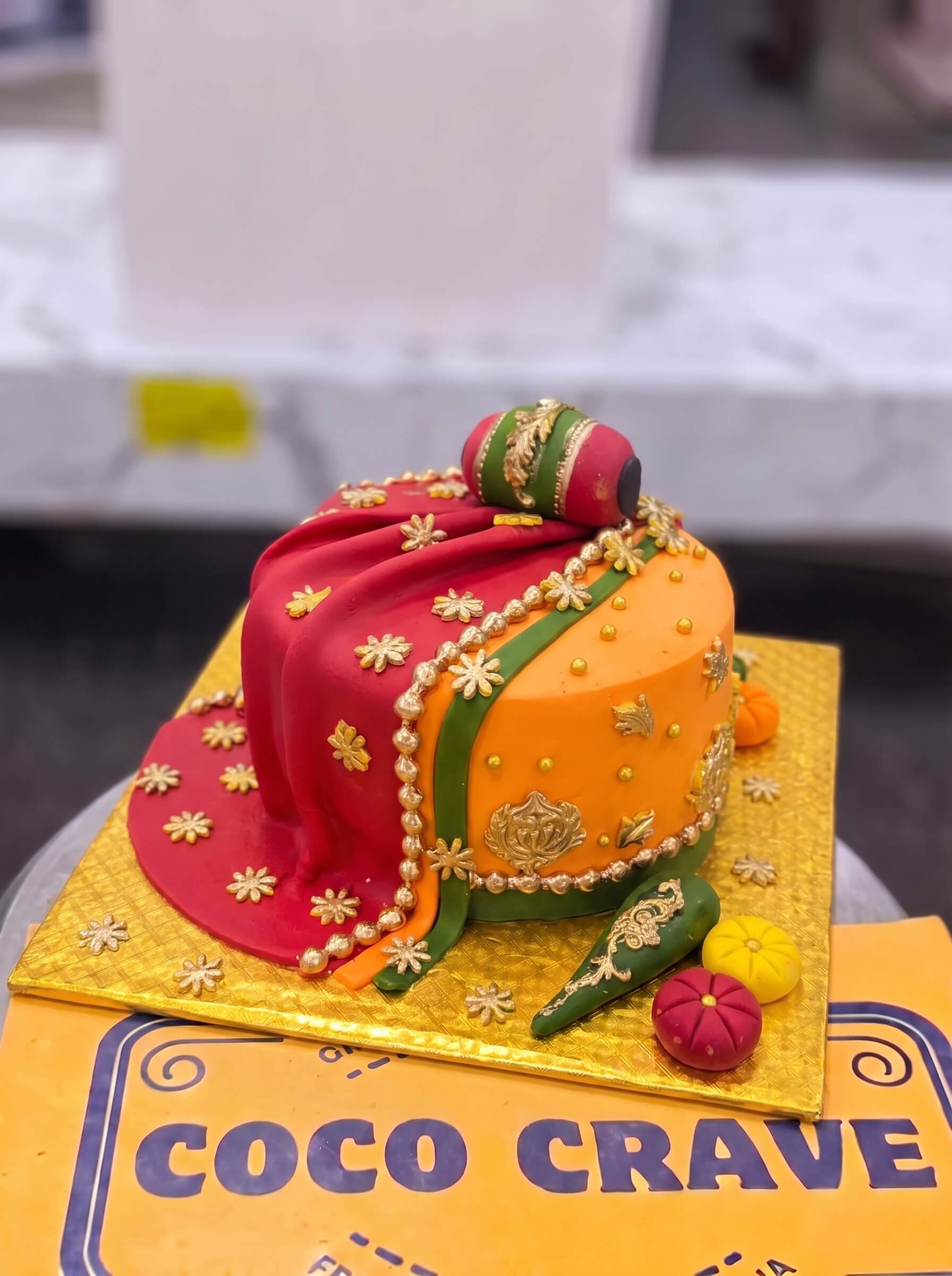 Maroon & Orange Dupatta Mehndi Cake in Lahore — Coco Crave Lahore Maroon & Orange Dupatta Mehndi Cake in Lahore — A maroon and orange fondant dupatta falling across a mehndi cake, edged in gold — the richest colourway in our