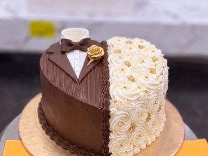 Chocolate Couple Heart Engagement Cake in Lahore — A couple heart cake with a chocolate suit on one side and ivory rose piping on the other — a chocolate engagem