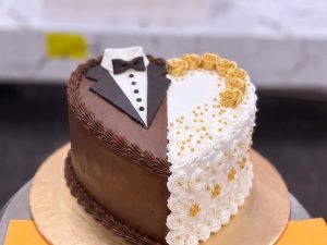 Bride and Groom Chocolate Heart Cake in Lahore — A heart cake split down the middle — a chocolate tuxedo on one side, an ivory-and-gold bridal side on the othe