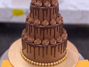 Three Tier Chocolate Drip Cake in Lahore — A three tier chocolate drip cake with piped chocolate swirls on every tier and a gold pearl base — a large cho