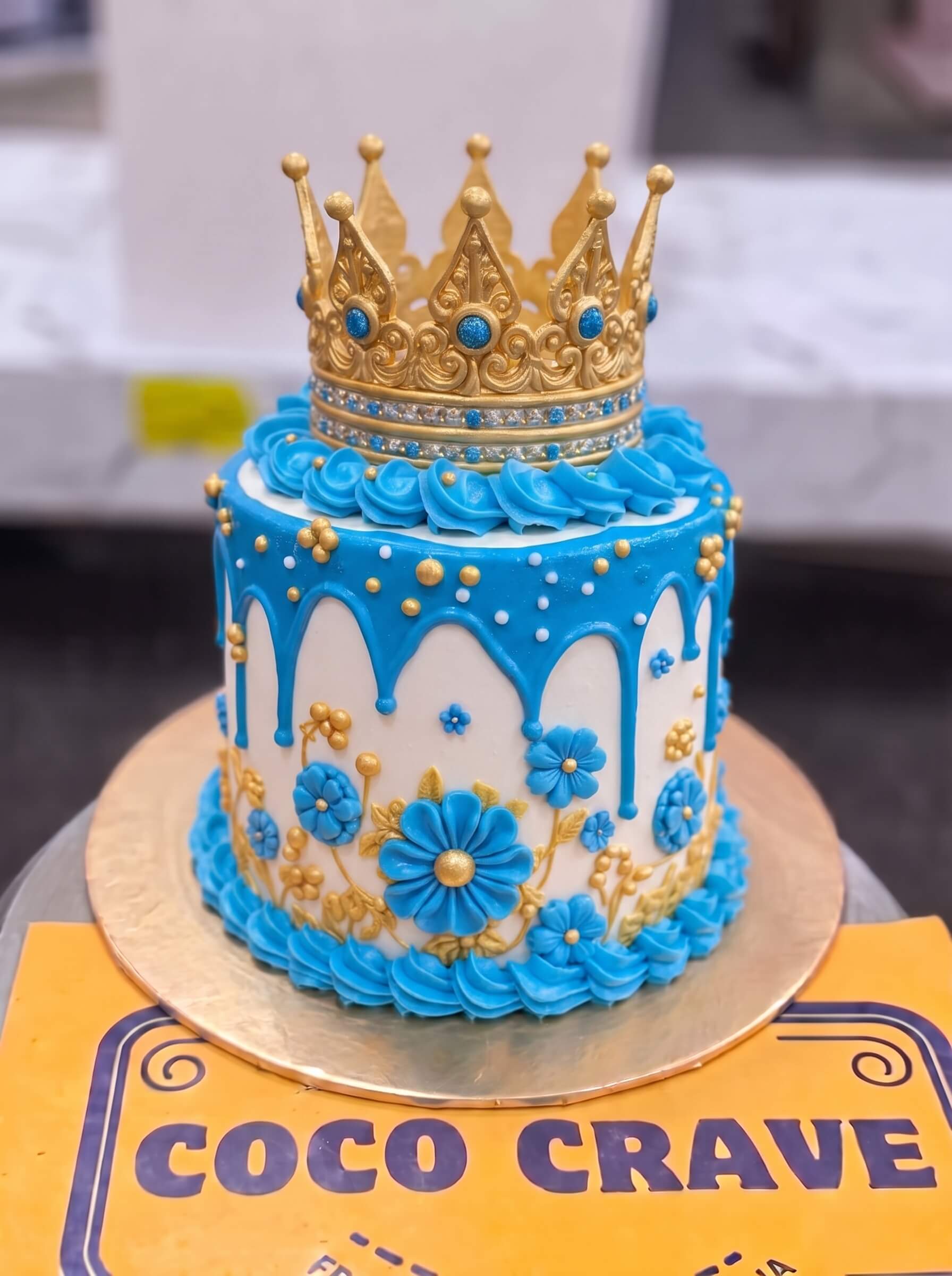 Move_crown_cake_to_image_2K_202609060425 Blue Floral Drip Crown Cake in Lahore — Cococrave Lahore