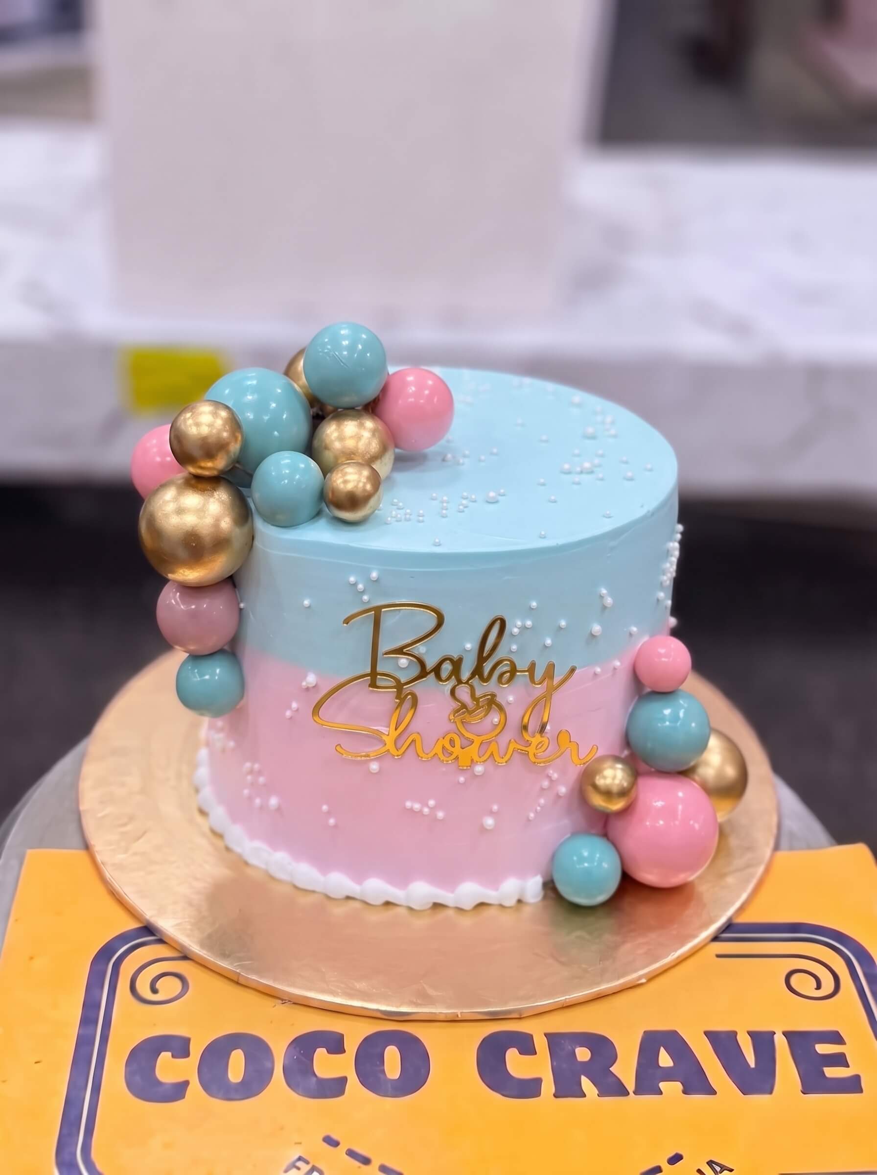 Baby Shower Balloon Cake in Lahore — CocoCrave.pk Baby Shower Balloon Cake in Lahore by CocoCrave.pk — single tier baby shower cake in blue, pink and gold
