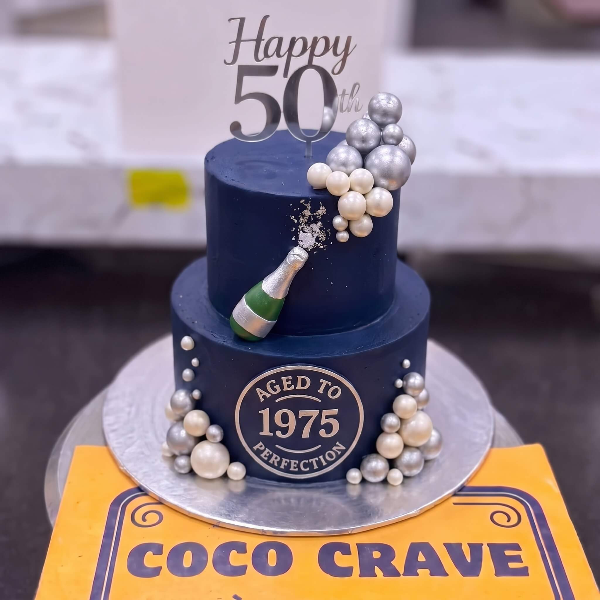 Navy Gold Fiftieth Birthday Champagne Cake in Lahore Navy Gold Fiftieth Birthday Champagne Cake in Lahore — CocoCrave Lahore